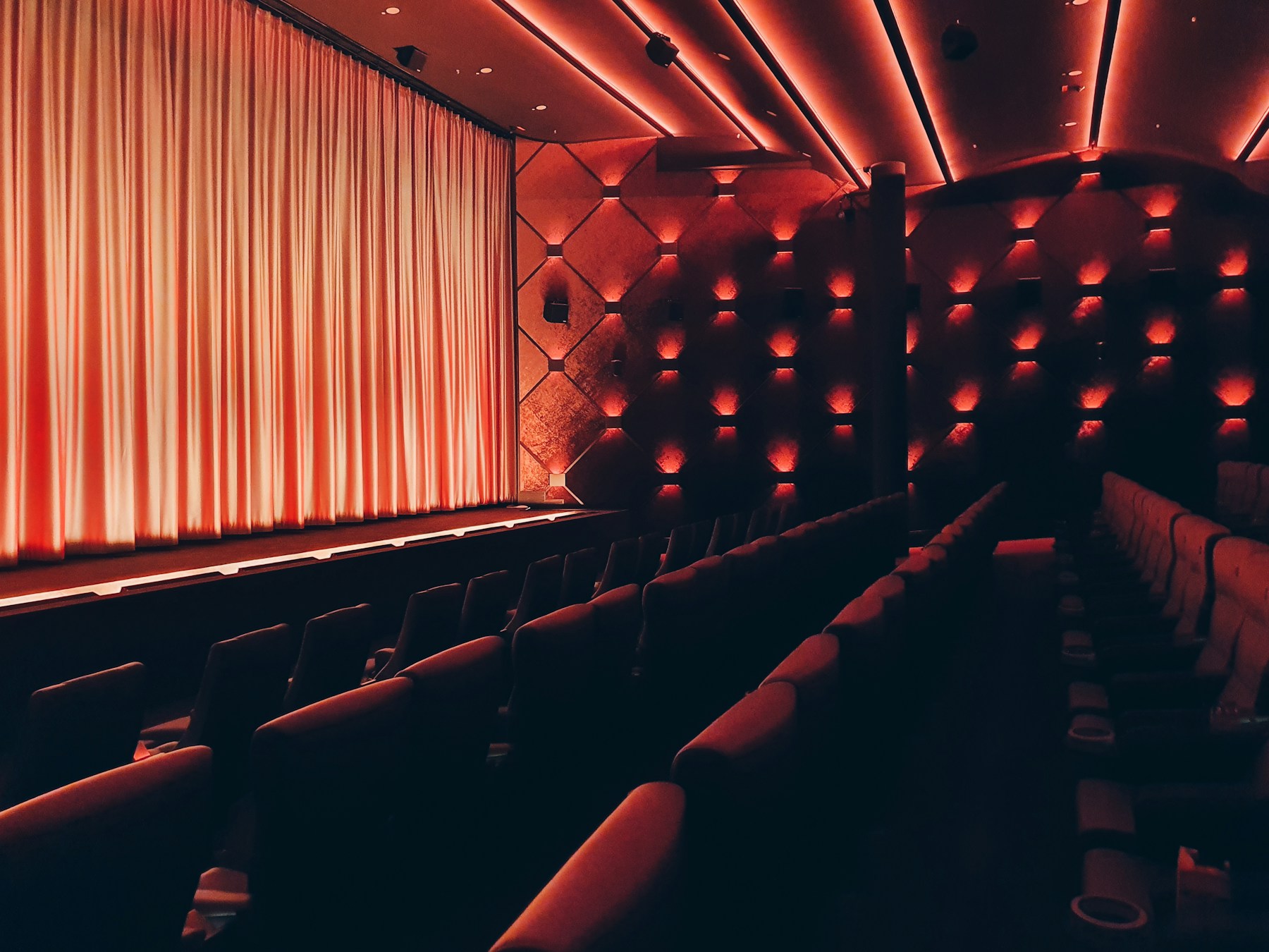 Warmly lit cinema curtains and empty seats, shown as a mood reference